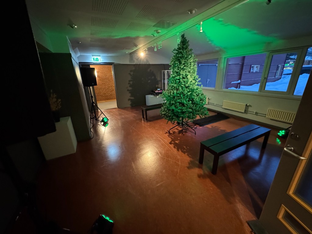 Wide interior view of Stemmetre i Åmot with the tree, projection, benches and loudspeakers